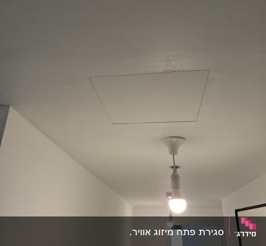 תקרה עם פתח גישה לגבס ומנורה תלויה